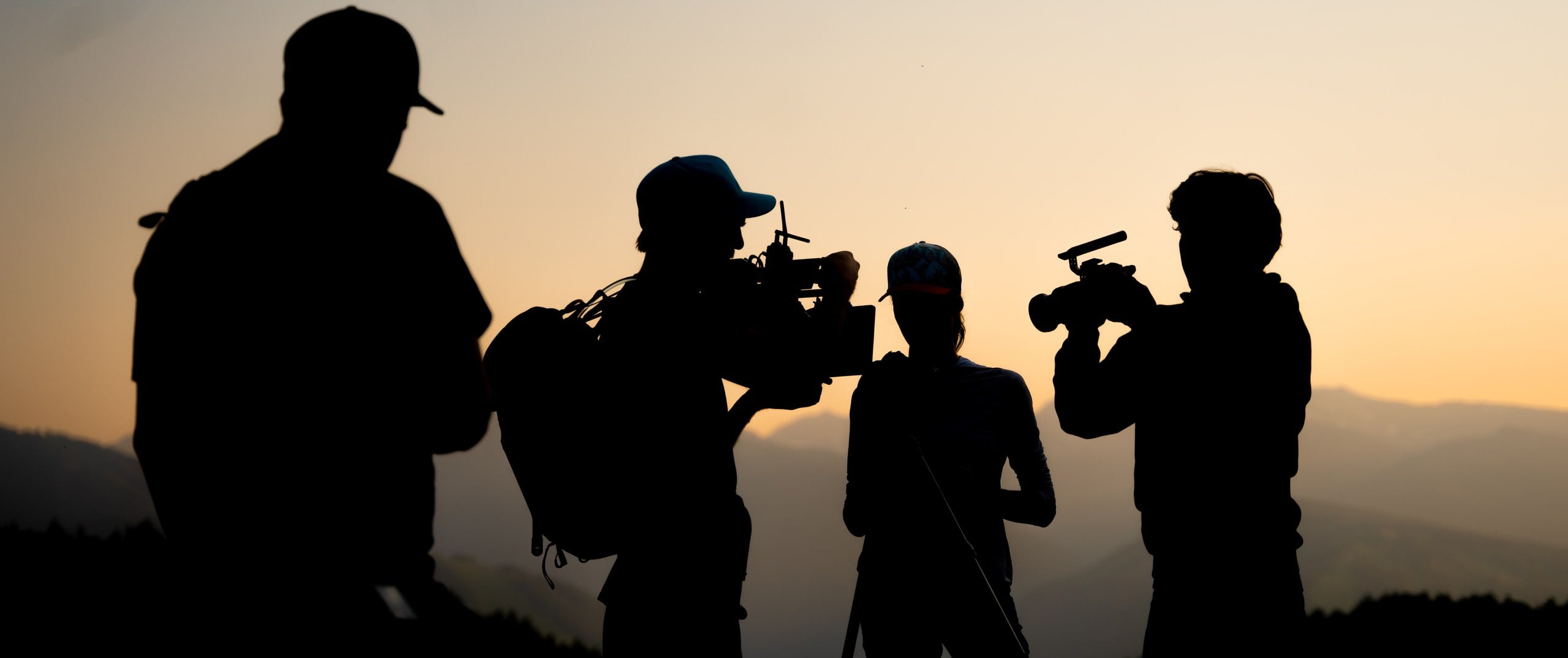 The Send It Productions crew filming with cinema cameras, silhouetted against a mountain sunset